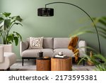 Small photo of The stylish composition at living room interior with green wall, design gray sofa, coffee table, dark lamp and elegant personal accessories. Beige pillow and plaid. Cozy apartment. Template.