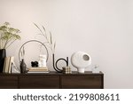 Small photo of Interior design of harmonized living room with brown commode, vase with flowers, candles, decoration, tea pot, book and elegant personal accessories. Stylish home decor. Template.