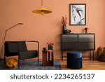 Interior design of cozy living room with mock up poster frame, glass sideboard, yellow lamp, navy pouf, carpet, black armchair, vase with dried flowers and personal accessories. Home decor. Template.