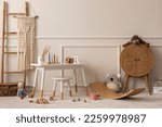 Small photo of Warm and cozy kids room interior with white desk, stool, rattan sideboard, stylish toys, plush monkey, koala, macrame, wooden blockers, beige rug and personal accessories. Home decor. Template.