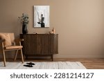 Creative composition of living room interior with mock up poster frame, copy space, wooden sideboard, vase with branch, rattan armchair, beige rug and personal accessories. Home decor. Template. 