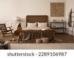 Small photo of Warm bedroom interior with mock up poster frame, cozy bed, beige bedding, stylish lamp, round box, black rack, wall with stucco, rattan armchair and personal accessories. Home decor. Template.