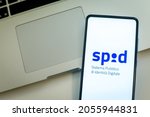 Small photo of Close up view of hand with smartphone and Spid - Sistema Pubblico Identita Digitale - logo on display. Laptop on background. Italian electronic signature. Milan, Italy - October 2021