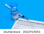 Bottle of covid-19 vaccine, dose record card, and medical syringe prepared at clinic for doctor to inject volunteer to activate immune people to prevent pathogen outbreak