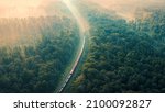 Small photo of Cargo Train in summer morning forest at fog sunrise. Aerial view of moving freight train in forest. Morning mist landscape with train, railroad, foggy trees. Top aerial drone view near railway.
