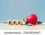 Small photo of Happy New Year 2024 for health care and medical concept.Wooden block with 2024 number and medical sign.Red heart and stethoscope.
