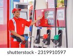 Small photo of Luwuk Banggai. Indonesia - June 9, 2023. A male worker at a Pertamina gas station shows a fuel filling machine starting from scratch, serving in a friendly manner.