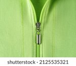 Small photo of Zip fastener of light green sweatshirt hoodie close-up. Fashionable summer cotton jacket with zipper fastening. Trendy clothes in bright colors, casual outerwear concepts. Half zipped pullover.