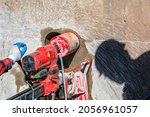Small photo of Worker is drilling to concrete wall with core drill machine in the construction site. A modern core drill is a drill specifically designed to remove a cylinder of material, much like a hole saw.