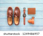 Men’s accessory with loafer shoe, wallet leather, brown watch and belt  isolated on a blue wooden background. Top view.