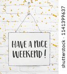 Text have a nice weekend white sign banner board with golden confetti on white brick background