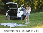 Young family three people in white clothes have picnic. Beautiful parents and daughter travel by car during summer vacation. Scene in park