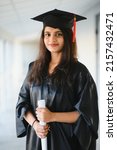Small photo of Happy Indian university student in graduation gown and cap holding diploma certificate.