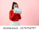 Photo portrait of excited woman holding gift box in two hands isolated on pastel pink colored background