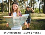 Small photo of Two happy children having fun during forest hike on beautiful day in pine forest. Cute boy scout with binoculars during hiking in summer forest. Concepts of adventure, scouting and hiking tourism.
