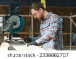 Wood cutting table with electric circular saw. Professional carpenter in uniform cutting wooden board at sawmill carpentry manufacturing . Sawing machine.