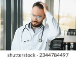 Stressed male doctor. Mid adult male doctor working long hours. Overworked doctor in his office. Not even doctors are exempt from burnout.