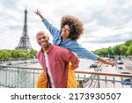 Small photo of Black cheerful happy couple in love visiting Paris city centre and Eiffel Tower - African american tourists travelling in Europe and dating outdoors