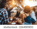 Small photo of Group of young happy friends having pic-nic outdoors - People having fun and celebrating while grilling ata barbacue party in a countryside
