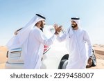 Small photo of Two middle-eastern men wearing traditional emirati arab kandura driving a 4x4 car in the desert - Arabian muslim friends meeting at the sand dunes in Dubai for an excursion