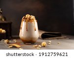 Sweet Milkshake with caramel syrup,cream liqueur,caramel popcorn and chocolate powder on brown background with vintage,manual coffee grinder.