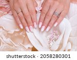 Female hands with ombre manicure nails, pink gel polish, on paper flowers background
