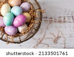 Silk-Dyed Easter Eggs in a Wire Basket on a White Background