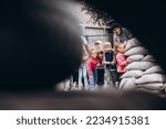 Small photo of 07.07.22 Irpin, Ukraine: children and their teachers walk in pairs holding a pen and hide in a roadblock made of sandbags during an air raid warning