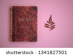 Small photo of diary book, day book, red autumn dry leaf on pink background, red old ancient book