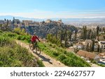 Small photo of nice active senior woman cycling with her electric mountain bike in Granada below the world heritage site of Alhambra, Granada, Andalusia, Spain