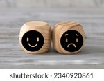 Small photo of Happiness and sadness concept. Two abstract geometric wooden dice isolate on white rustic surface. Antagonism concept.