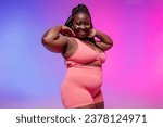 Small photo of Voluptuous African woman in sportswear radiating self-love while standing on vibrant background