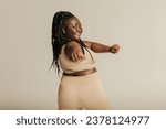 Small photo of Rear view of voluptuous African woman in sportswear exercising on studio background