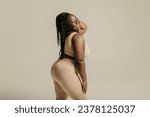 Small photo of Side view of voluptuous young African woman in underwear radiating joy and self-love