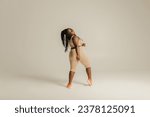Small photo of Full length rear view of voluptuous African woman in sportswear dancing on studio background