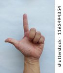 Small photo of Left Hand, L-sign underhand, “Loser” symbol. Asian male hand model.