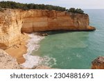 Small sandy beach surrounded by limestone cliffs at the Atlantic Ocean on a sunny winter day along the Seven Hanging Valleys Trail in southern Portugal.