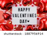 Stylish text frame lightbox with the inscription happy Valentine's day. Pink, red and beige hearts all around. Foil balloons top view of Valentine's Day. Copyspace.