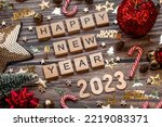 Banner. The symbol of the number 2023 with gold and red balls, stars, sequins and a Christmas tree on a wooden background. The concept of celebrating a Happy New Year 2023 and Christmas.