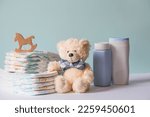 Small photo of Wooden toys, a bear in a bow tie, a stack of diapers, bottles without labels and baby supplies on the changing table. Space for text.