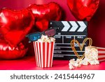 A banner for the film industry. A romantic movie date. A movie camera, 3D glasses, popcorn and heart-shaped foil balloons on a red background. The premiere of the film is on Valentine's Day.