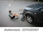 Small photo of Careless man felt down from electric scooter. Young male lying on back after falling from his vehicle. Mused male collided with a car and hurted his knees.Ivano-frankivsk, Ukraine - 09.07.2023.