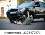 Small photo of Careless man felt down from electric scooter. Young male lying on back after falling from his vehicle. Mused male collided with a car and hurted his back.