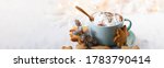 Small photo of Hot winter drink: chocolate with whipped cream in blue mug. Christmas time. Cozy home atmosphere, white background. Homemade gingerbread cookies, christmas lights. Banner, copy space for text