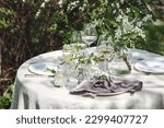 Rustic zero waste wedding decor with natural elements. Fresh spring blooming flowers, candles, linen napkins, wine glasses. Eco friendly decoration for the special holiday dinner. Romantic cozy place