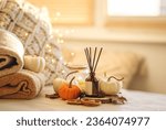 Autumn mood, cozy fall home atmosphere. Aroma diffuser, pumpkins, knitted warm sweaters, burning candles, dry leaves on wooden table. Concept of house decor, apartment seasonal fragrance. Thanksgiving
