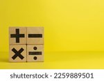 Small photo of Image of wooden cubes displaying mathematical operation icons of Plus, minus, multiply and divide on a yellow background in left side photo with copyspace use for education,mathematic,symbol concept.