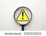 Small photo of Magnify glass focus on Exclamation mark on a yellow sing or Warning sign over white background Attention sign,Exclamation mark,warning sign concept.