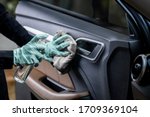 Car disinfecting service. Woman disinfecting and cleaning the inside handle of the car door. Safety and preventing infection of Covid-19 virus, contamination of germs or bacteria, wipe clean surfaces