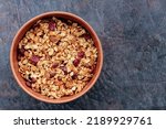 Granola with nuts and dried fruit on a dark background. Homemade granola in a clay bowl. Top view. Copy space